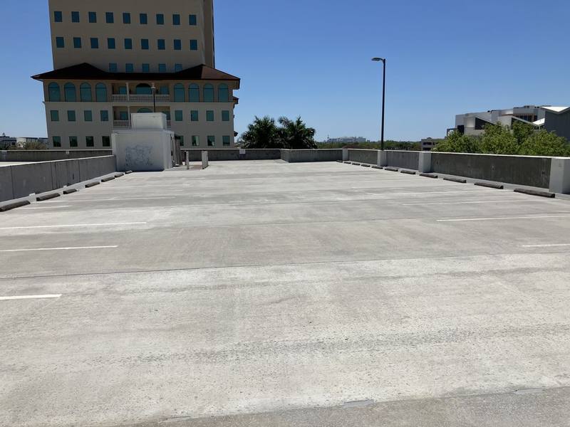 Top deck of the same kind of parking garage after cleaning, a lighter even gray with the painted lines easier to see