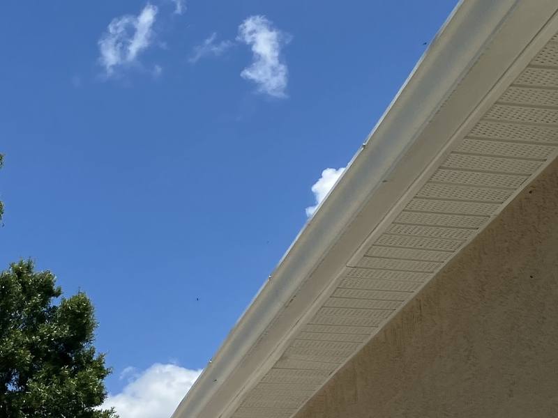 Bright white soffit, fascia and gutter along a roof edge after cleaning, against a blue sky