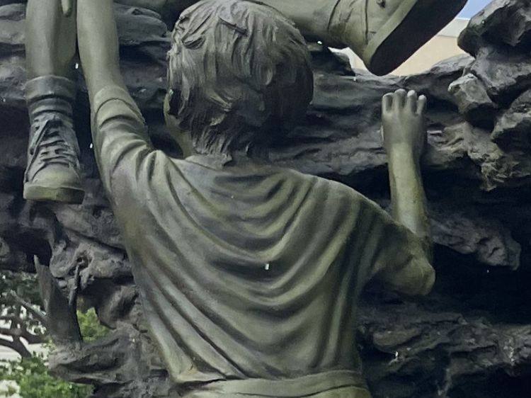 The same bronze statue after cleaning, a dark green-bronze color with the detail showing